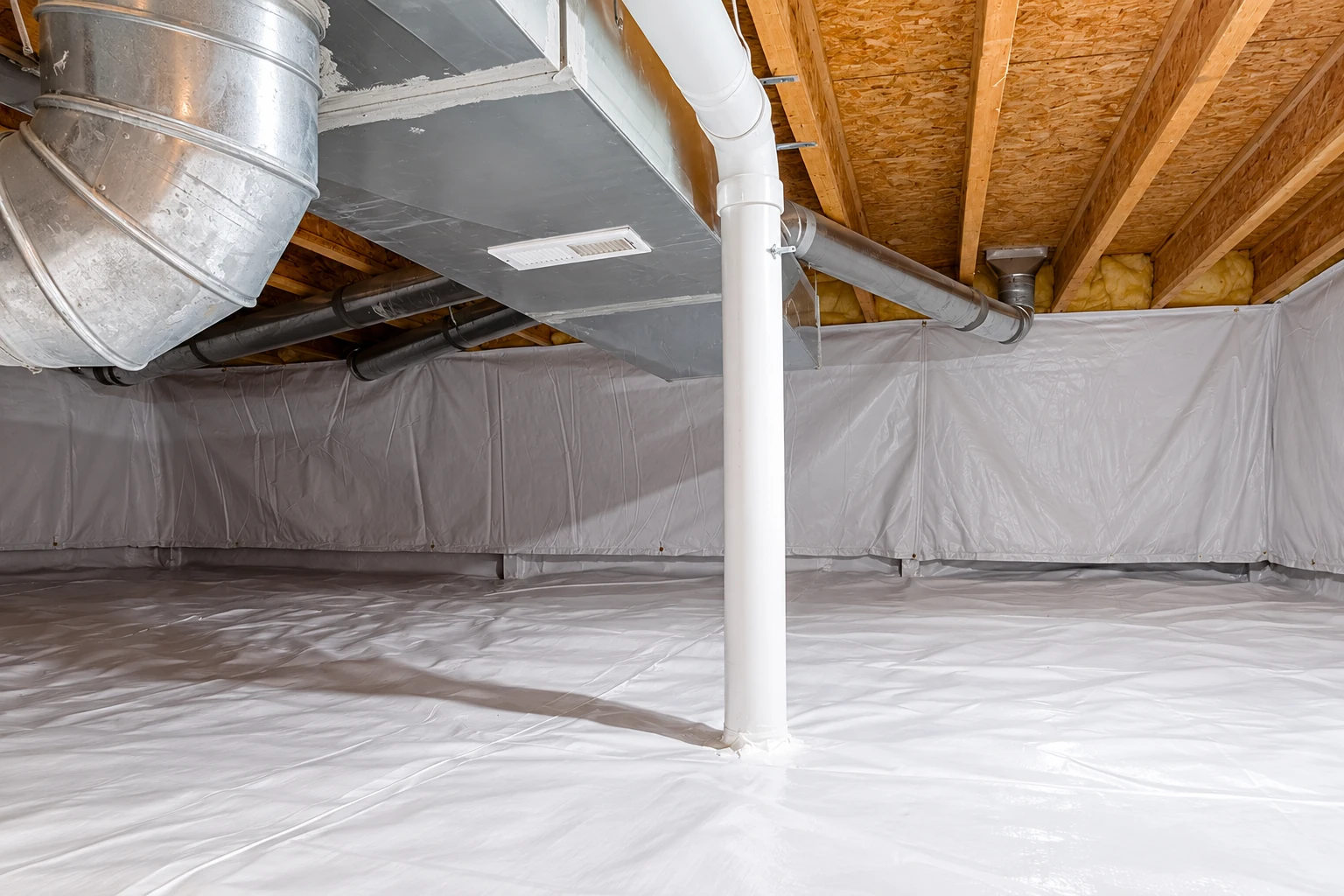 White vapor barrier sheeting covers the floor and walls of a crawl space beneath exposed joists, pipes, and ductwork.